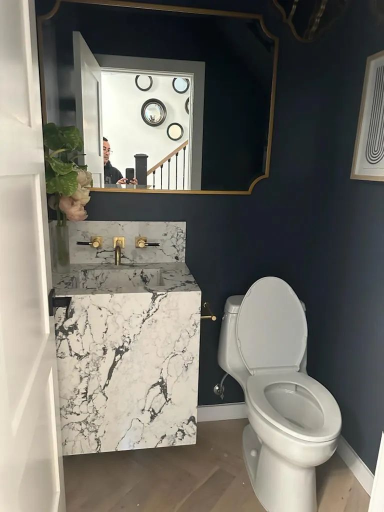 A bathroom with a toilet , sink and mirror.