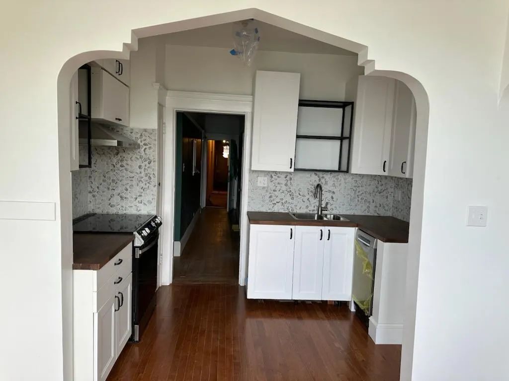 A kitchen with white cabinets , a stove and a sink.