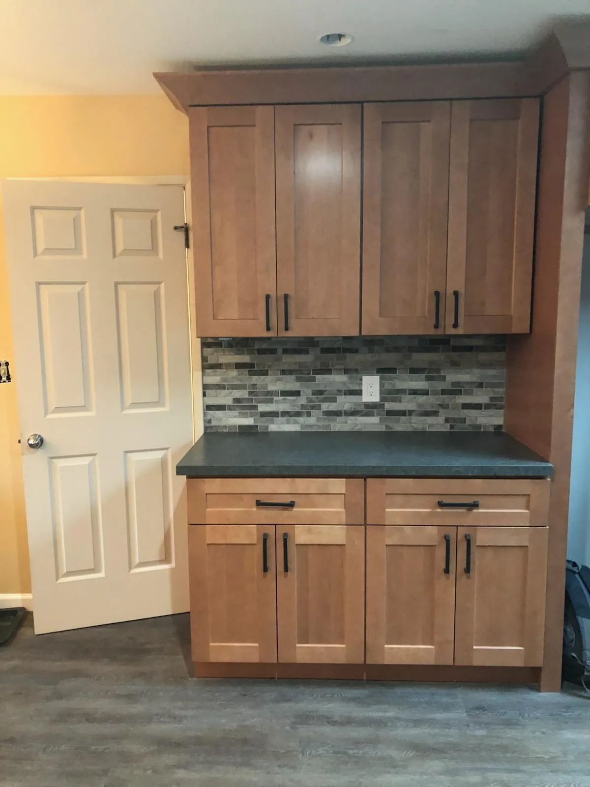 A kitchen with wooden cabinets and a black counter top