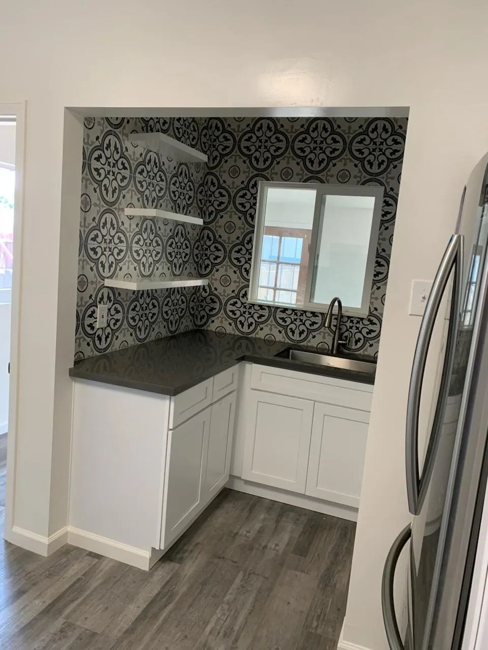 A kitchen with white cabinets , a sink , and a refrigerator.