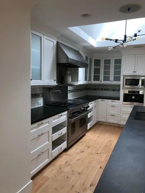 A kitchen with white cabinets and black counter tops