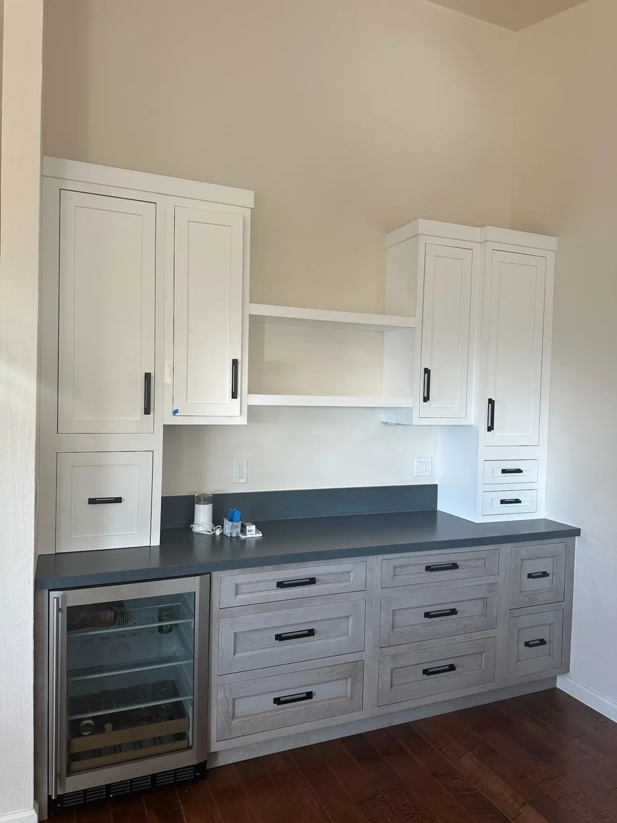 A kitchen with white cabinets and a stainless steel refrigerator.