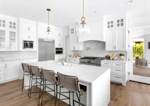 A kitchen with white cabinets , stainless steel appliances , and a large island.