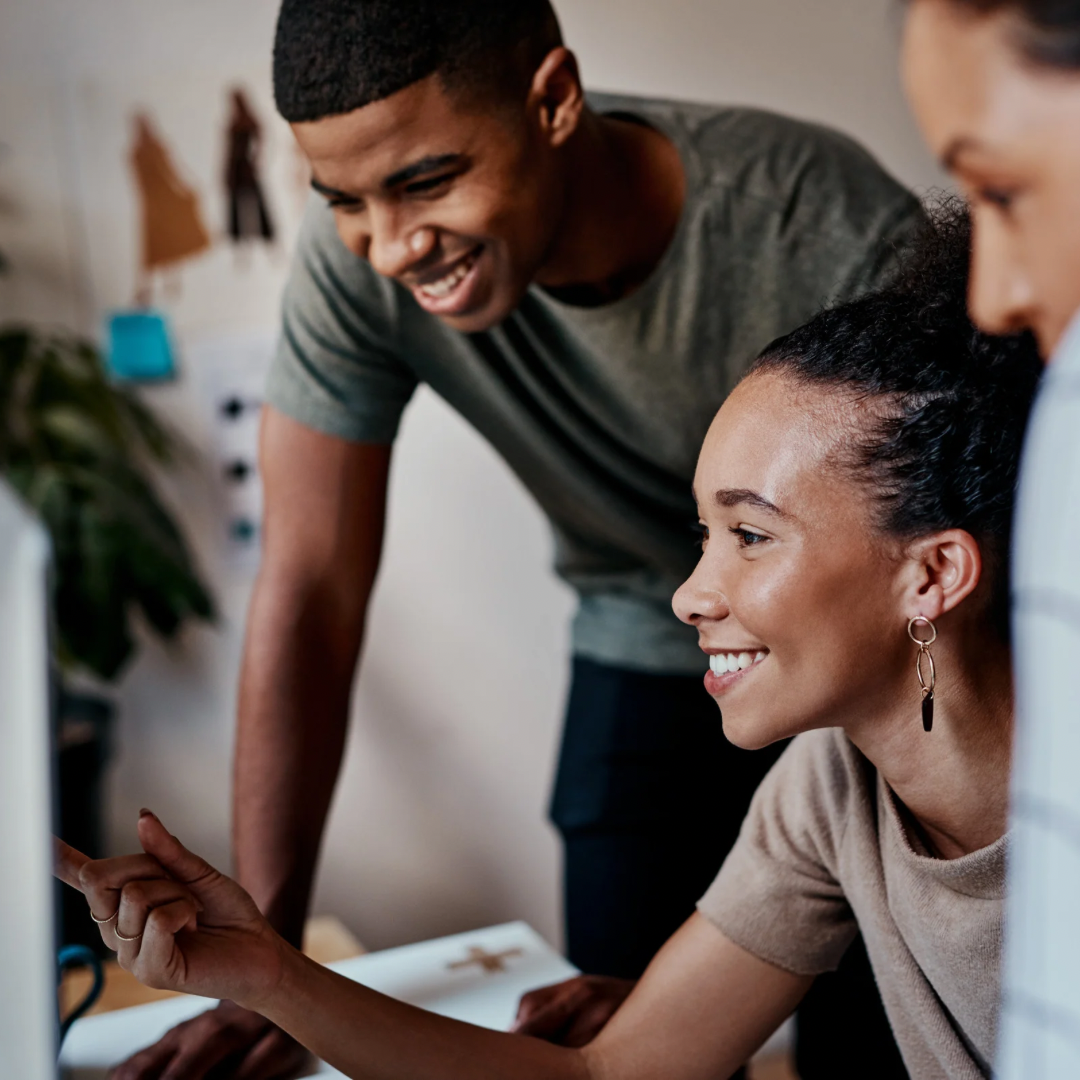 A group of people are looking at a computer screen and smiling.