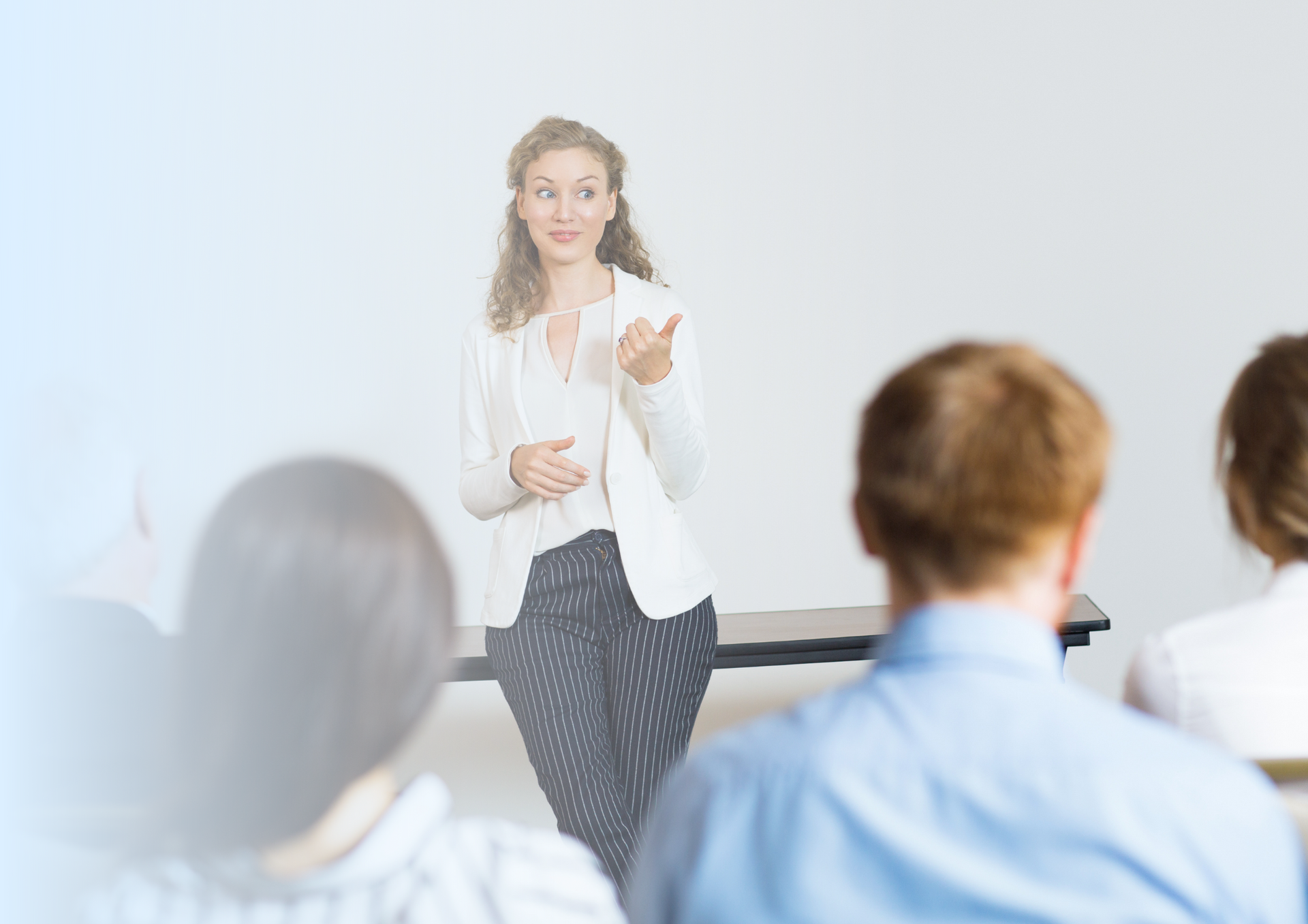 A woman is giving a presentation to a group of people in a classroom.