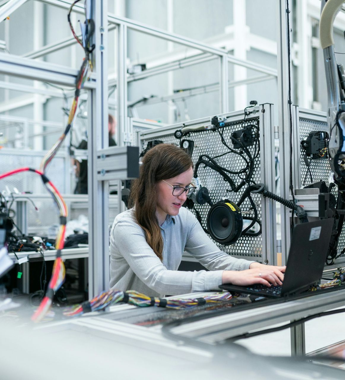 A woman is using a laptop computer in a factory.