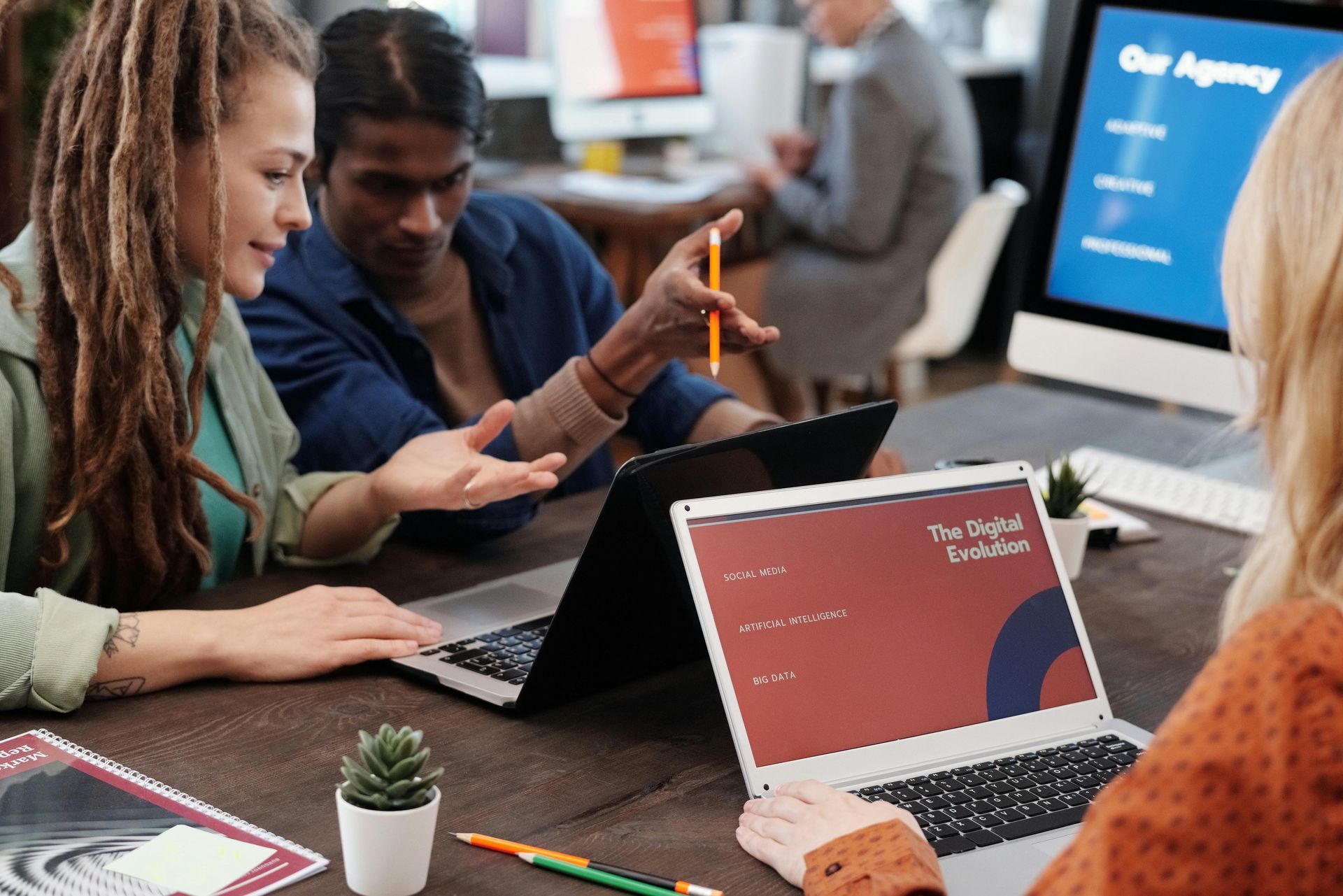 A group of people are sitting around a table looking at laptops.