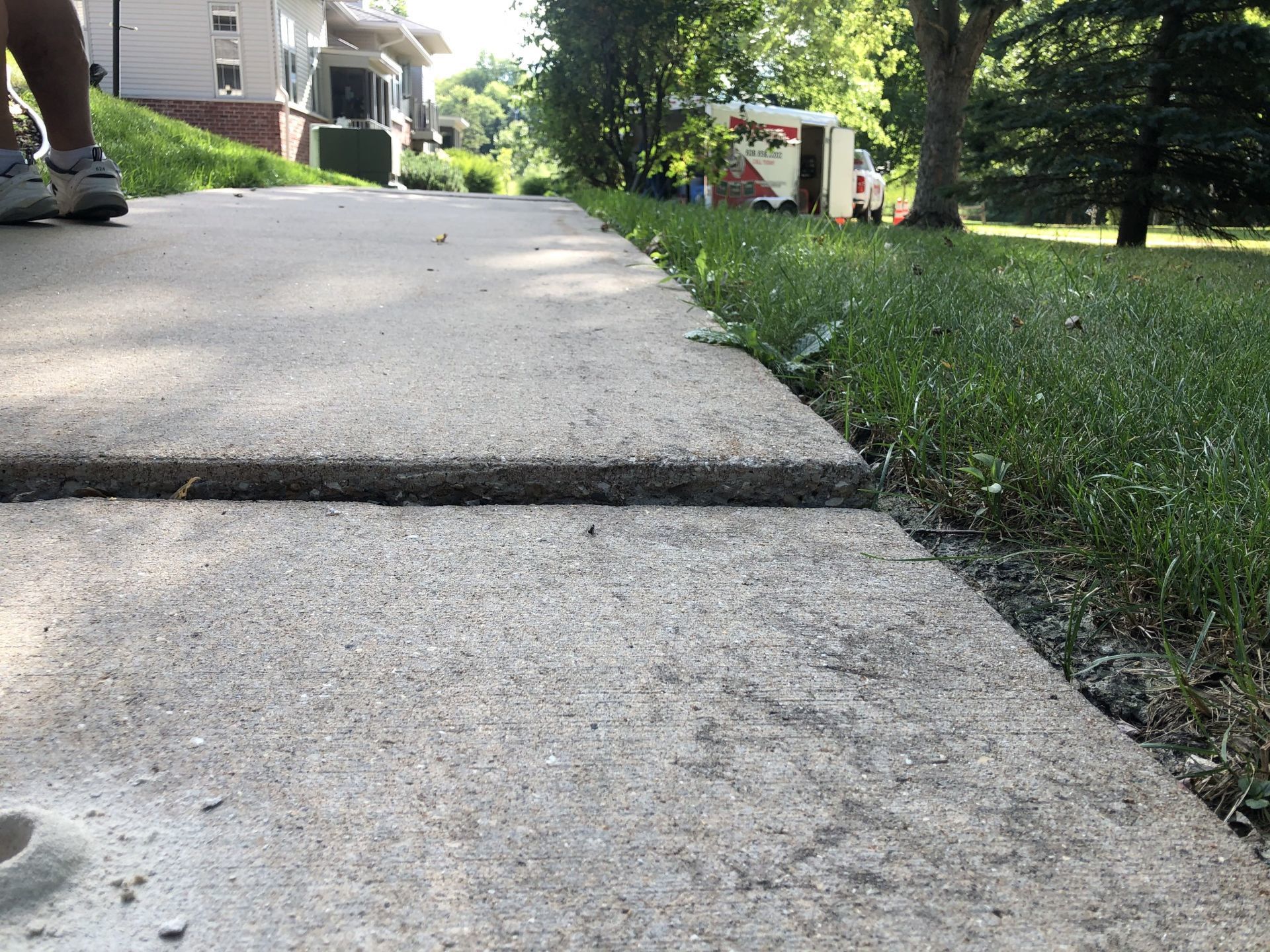 A person is walking down a sidewalk next to a grassy area.
