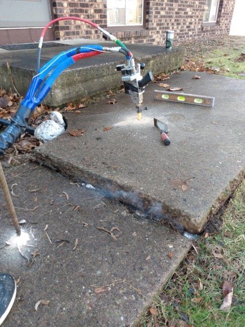 A machine is cutting a hole in a concrete sidewalk.