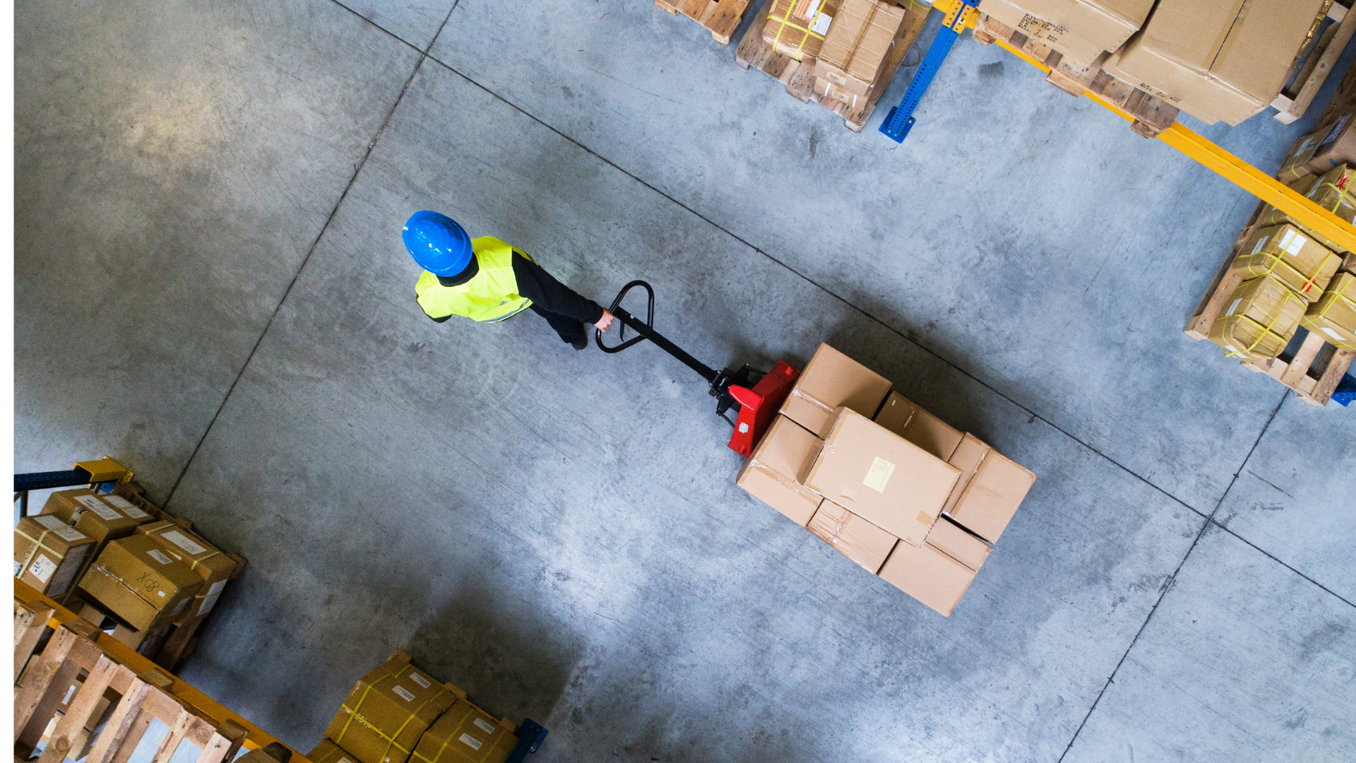An aerial view of a man pushing a pallet truck in a warehouse.