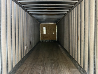 The inside of a shipping container with a wooden floor and a window.