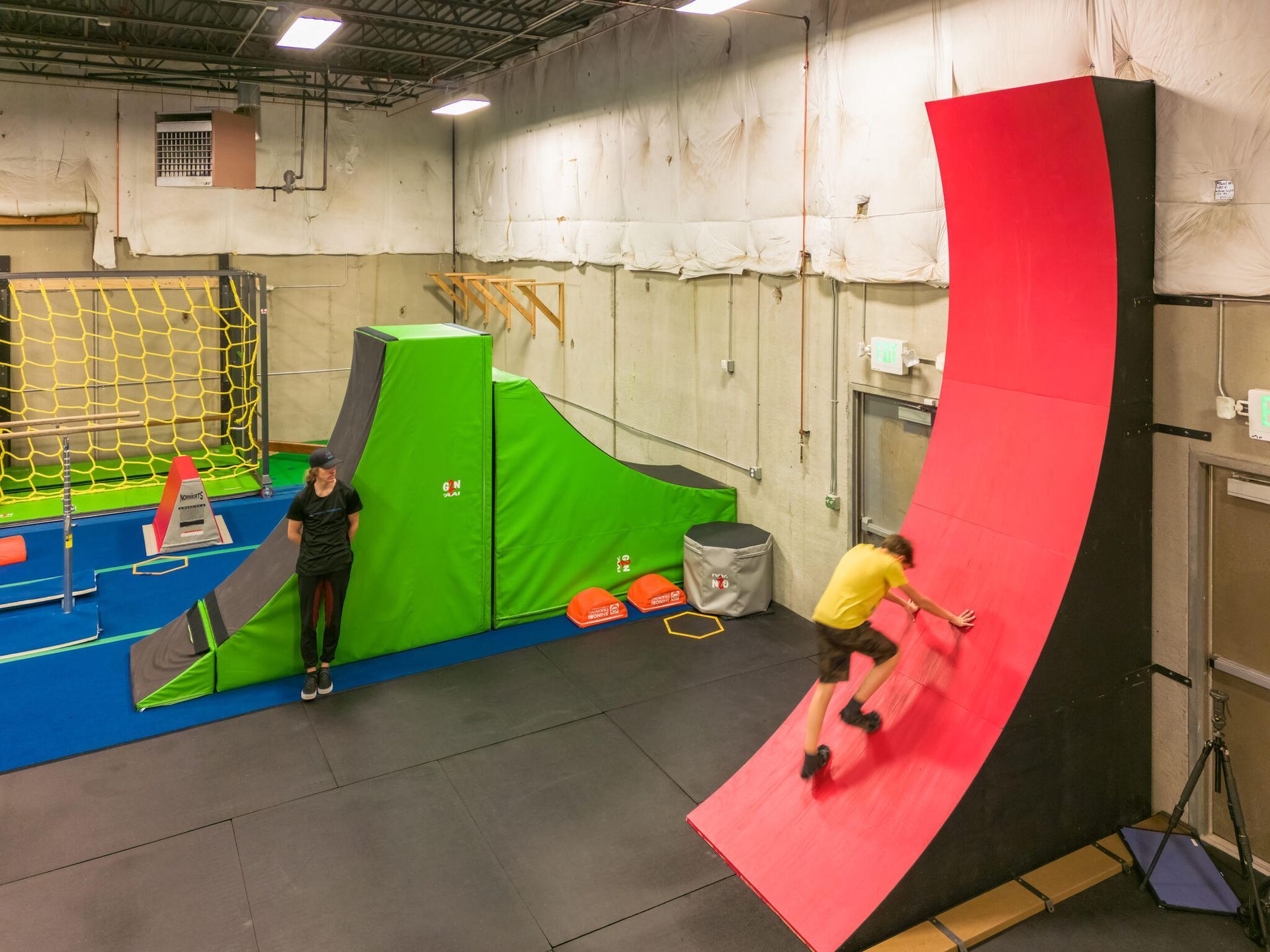 A boy climing the warp wall in ninja and parkour class
