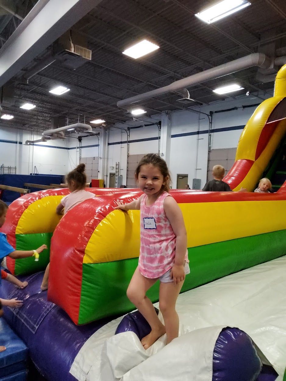 A little girl is standing on top of an inflatable slide.