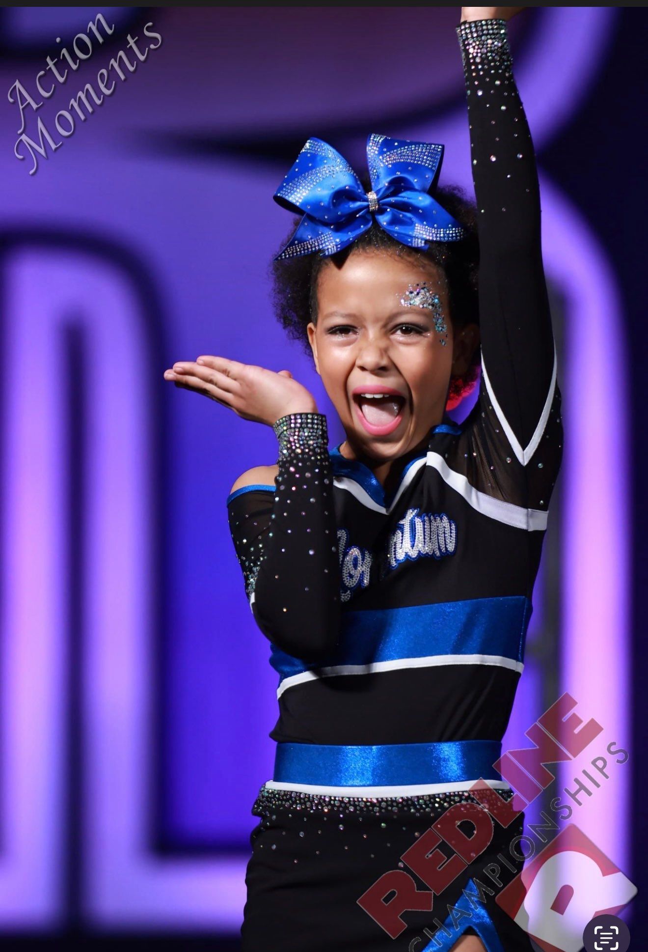 A cheerleader with a blue bow on her head is wearing a black and blue outfit
