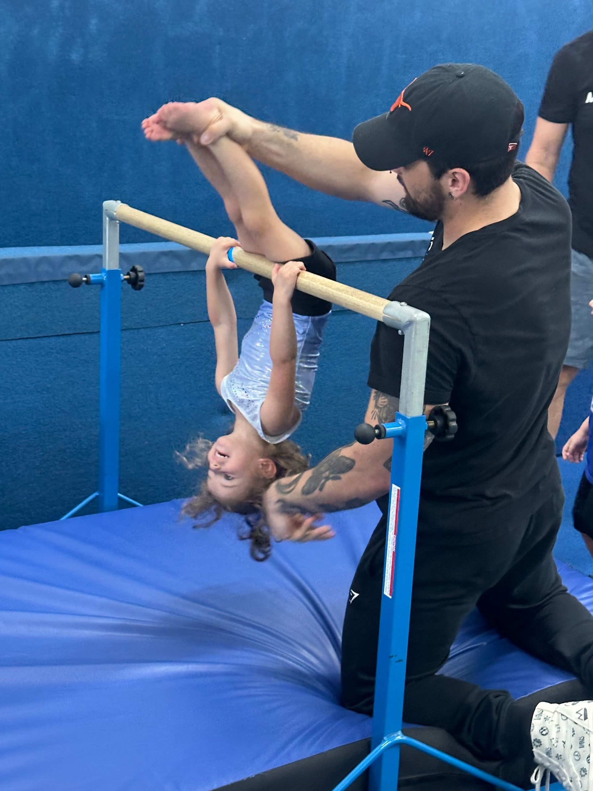 A toddler girl is learning skills in a gymnastics class