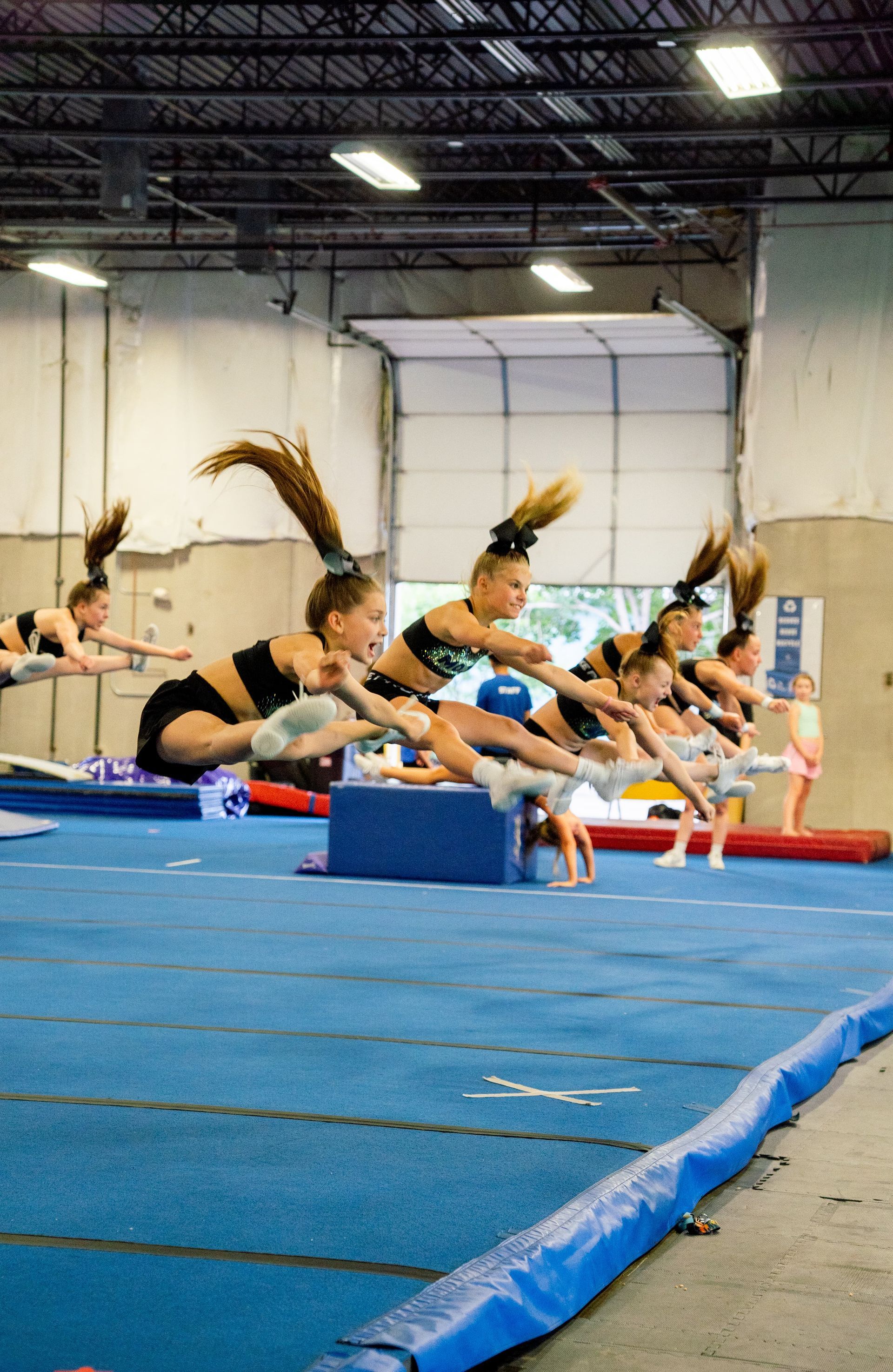 A group of middle school age girls learning a cheer tumbling stunt