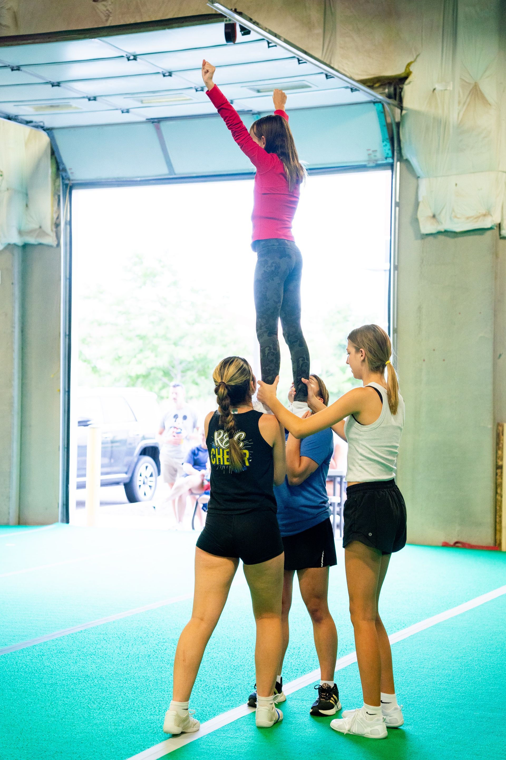 A group of middle school age girls learning a cheer stunt