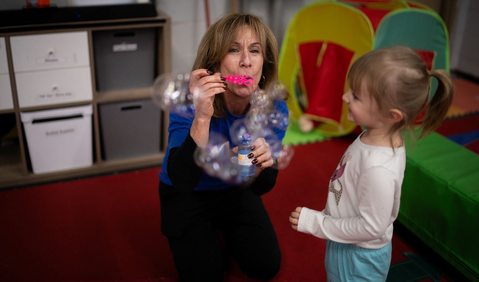 coach and developmental pathways speciaist blowing bubbles with developmentally disabled preschooler