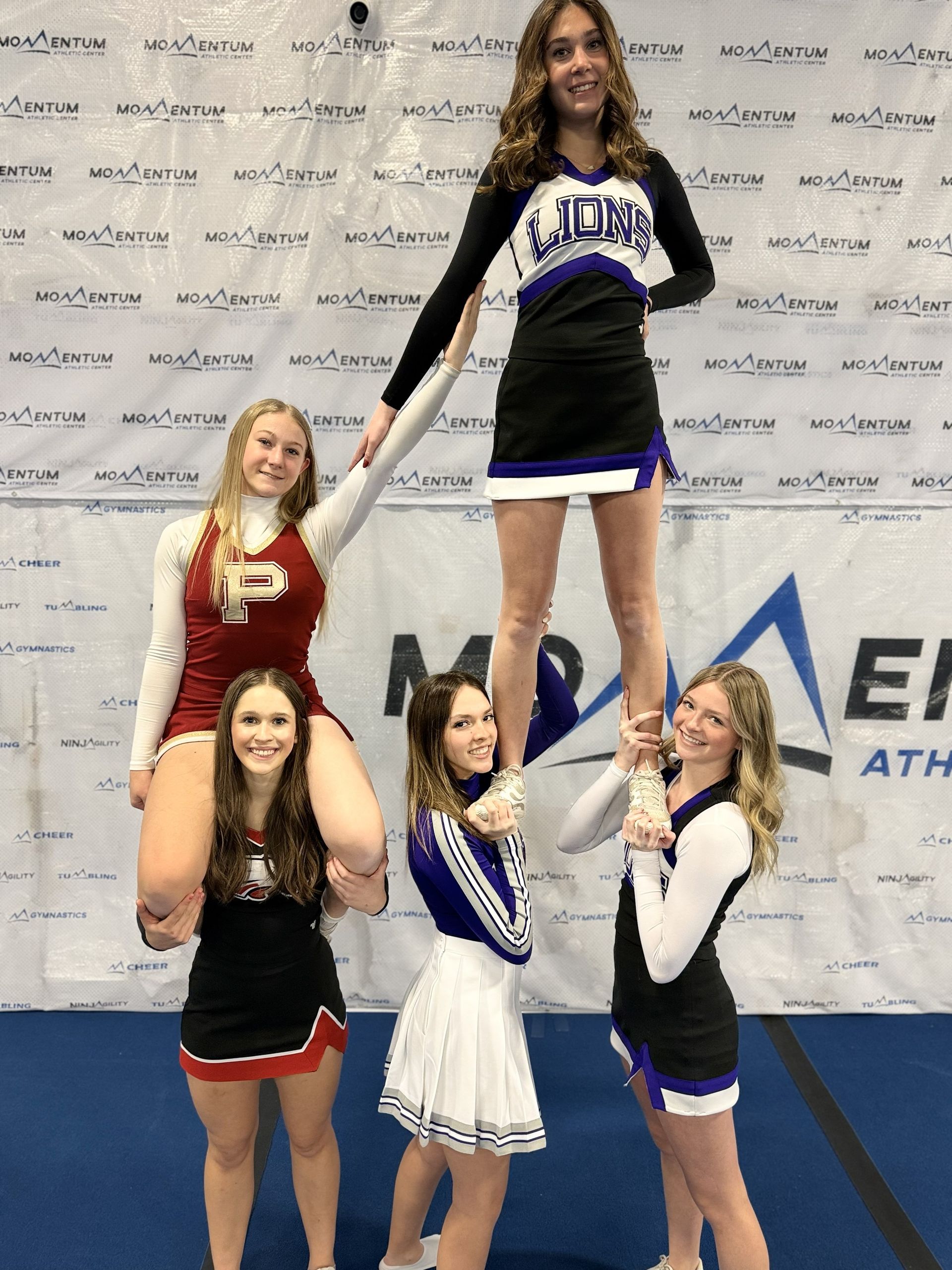 A group of middle school age girls learning a cheer stunt