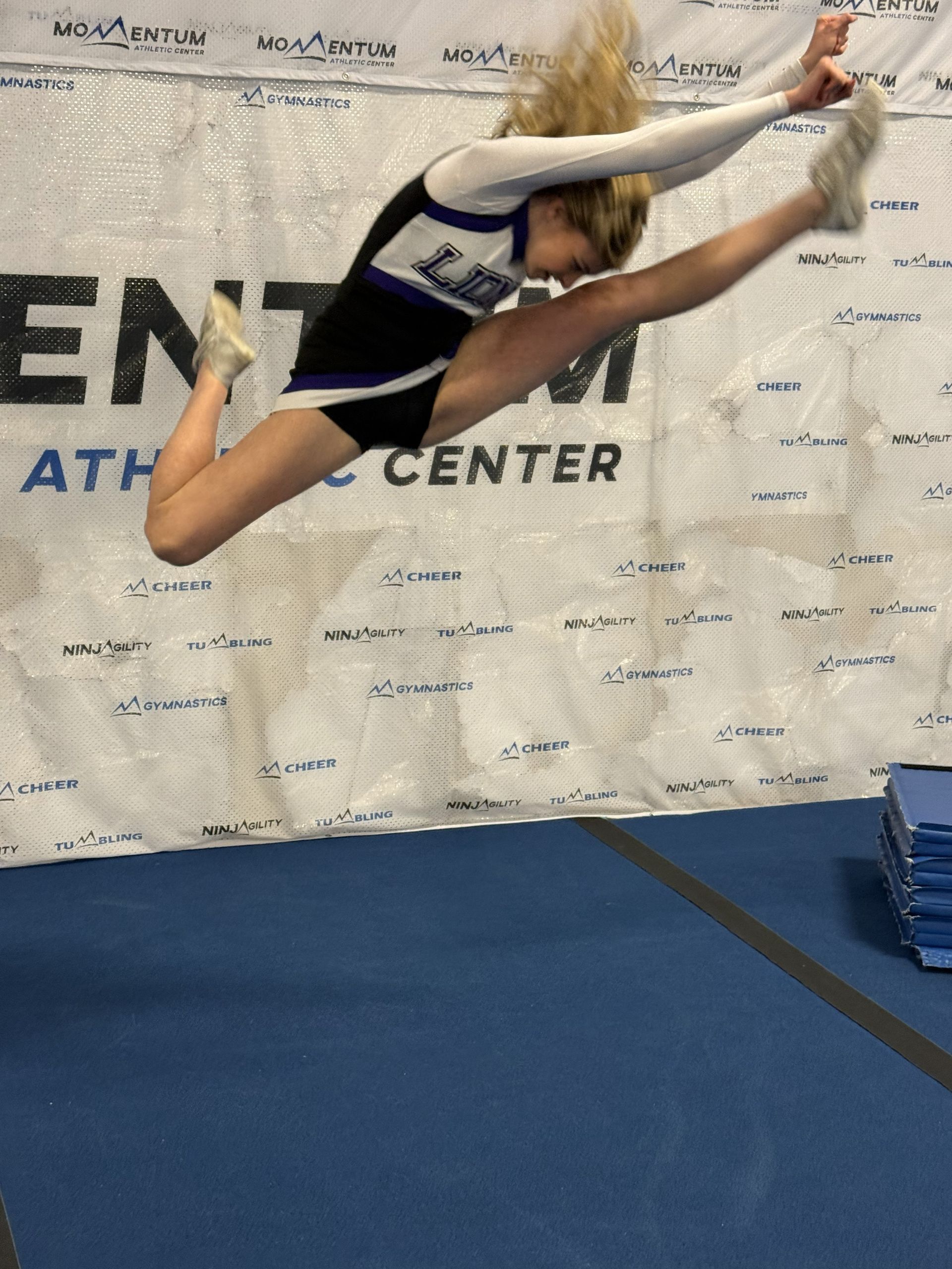 A group of middle school age girls learning advanced high school cheer tumbling stunt