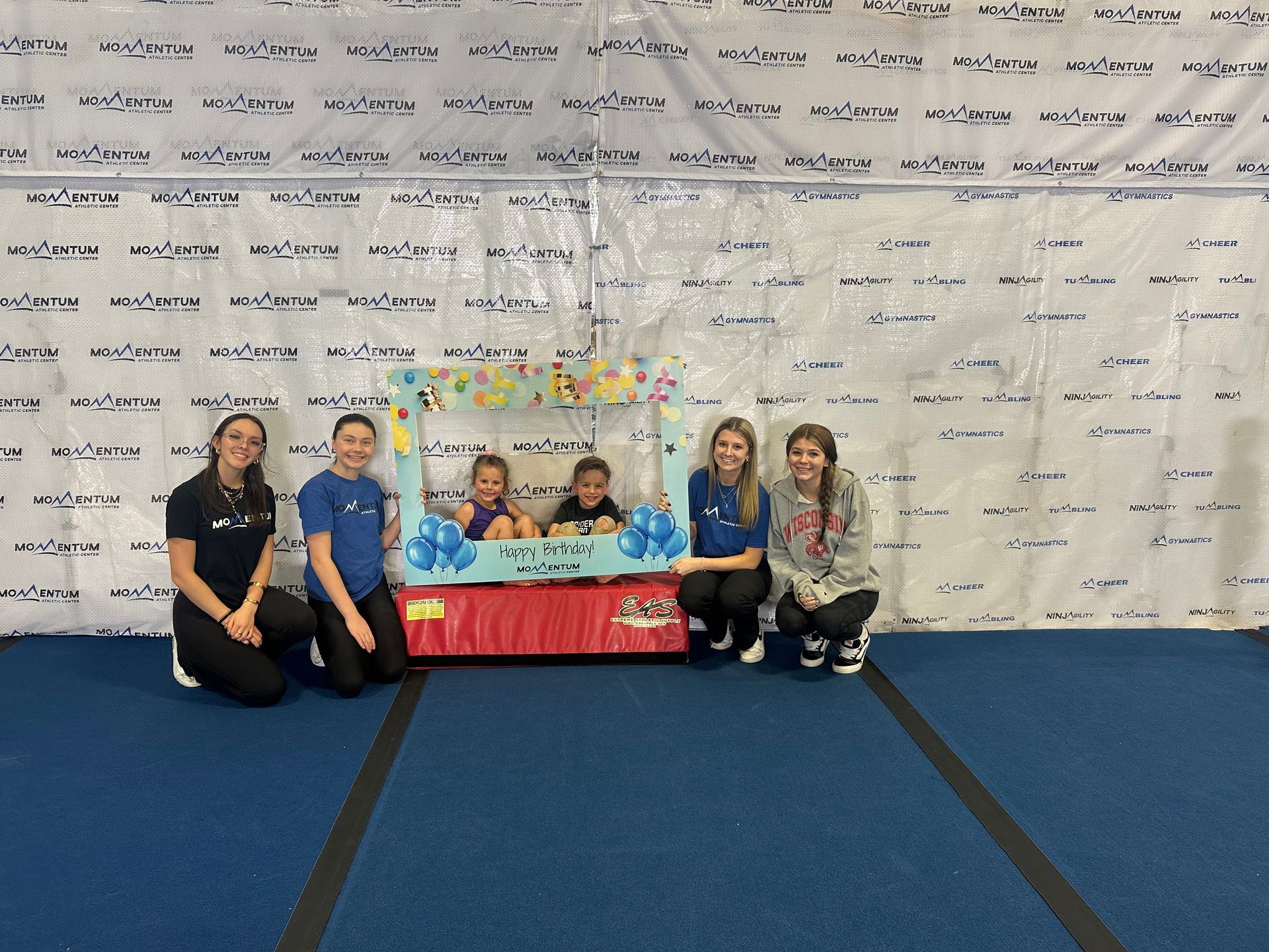 A group of young girls are posing for a picture in a gym.