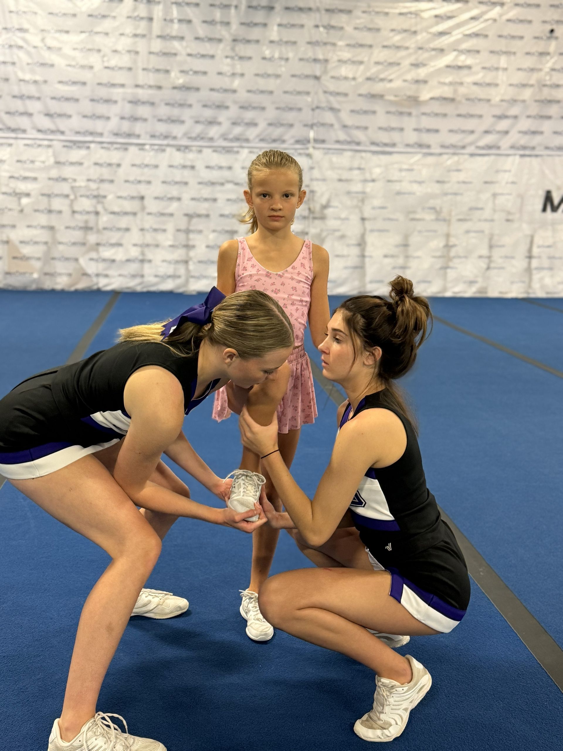 A group of middle school age girls learning a cheer tumbling stunt