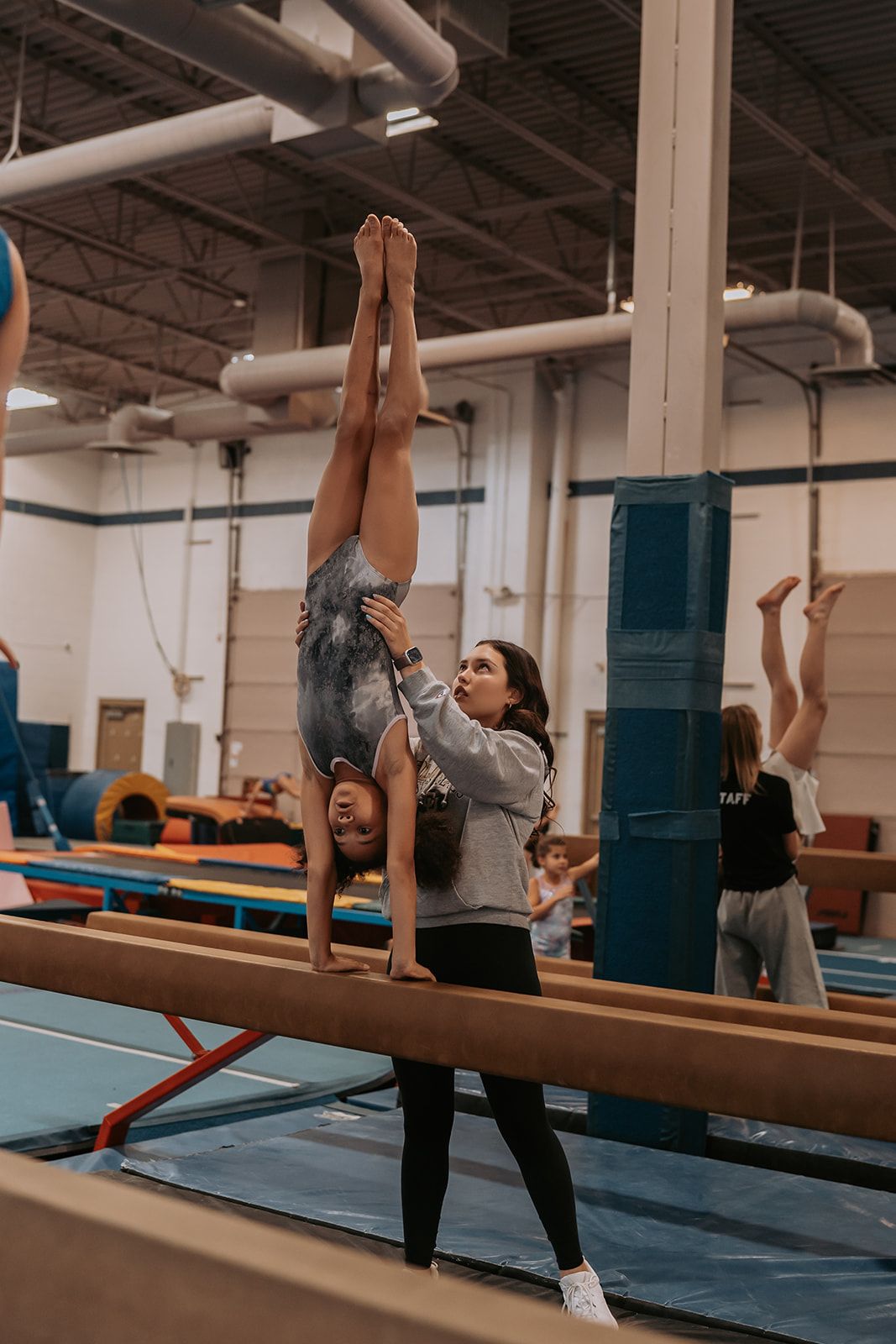 A young girl  on a balance beam in a gym.