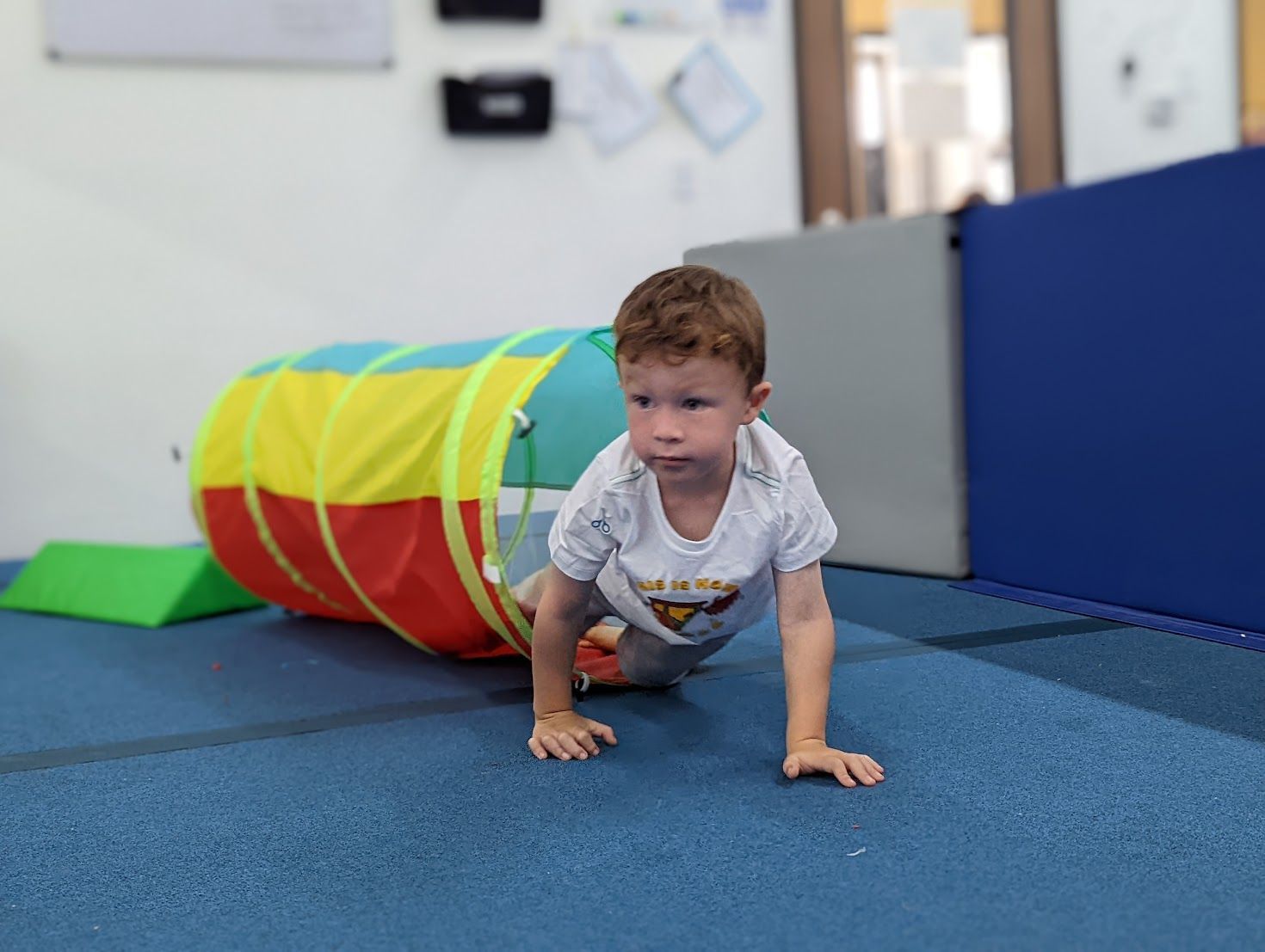A young boy is crawling through a tunnel on the floor.