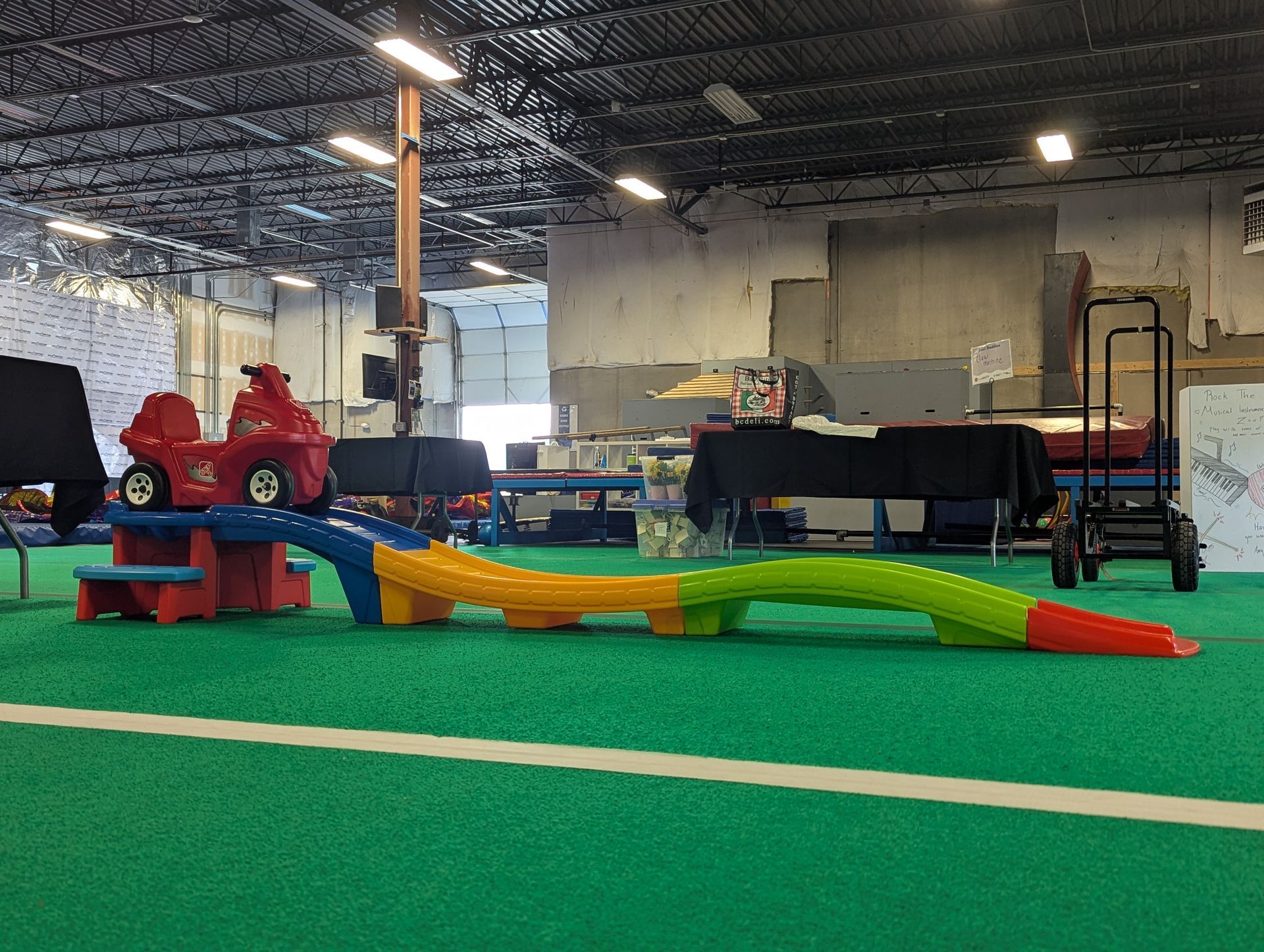 A toy car is sitting on top of a green carpet in a warehouse.