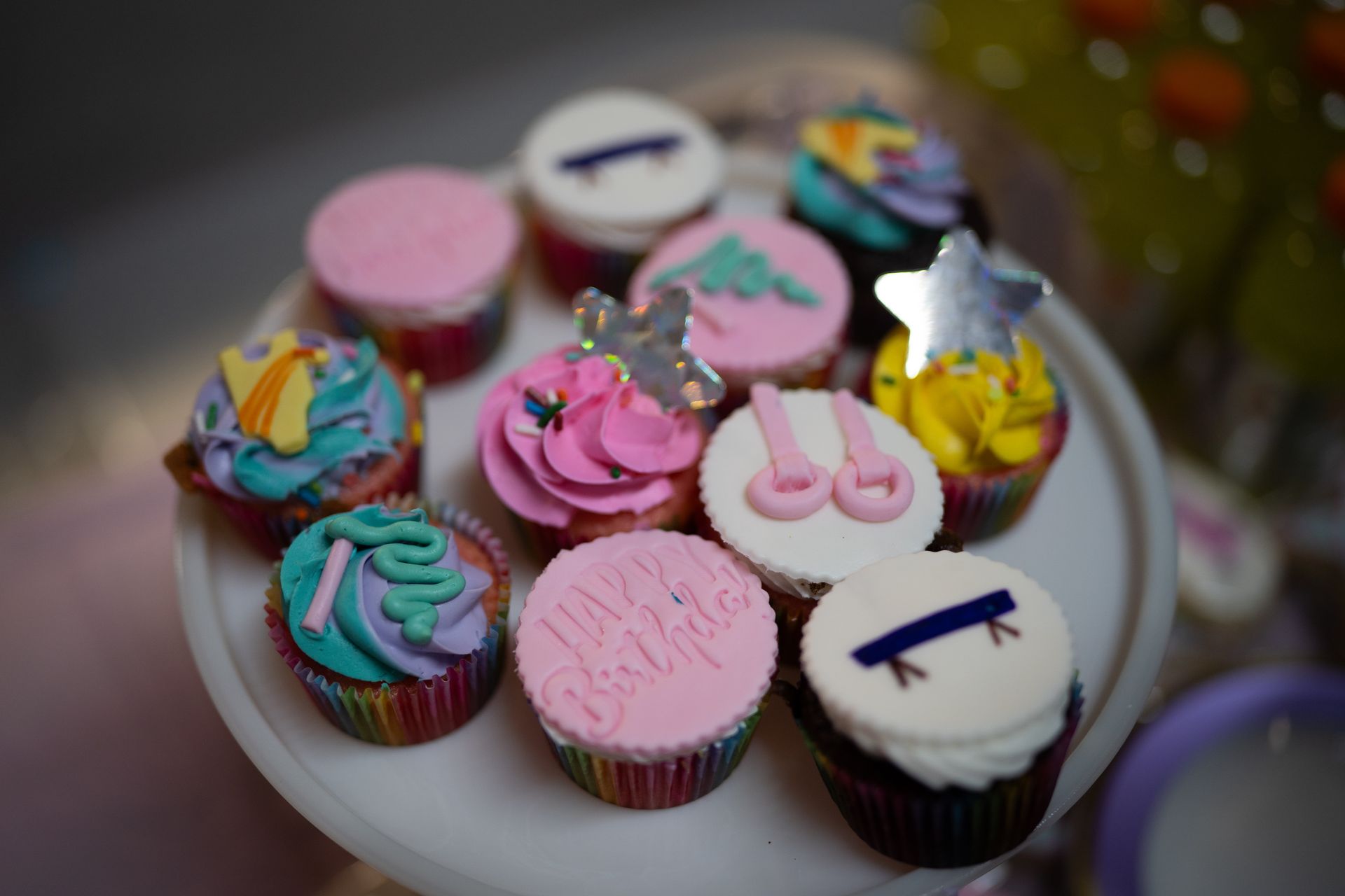 A bunch of colorful birthday cupcakes on a white plate