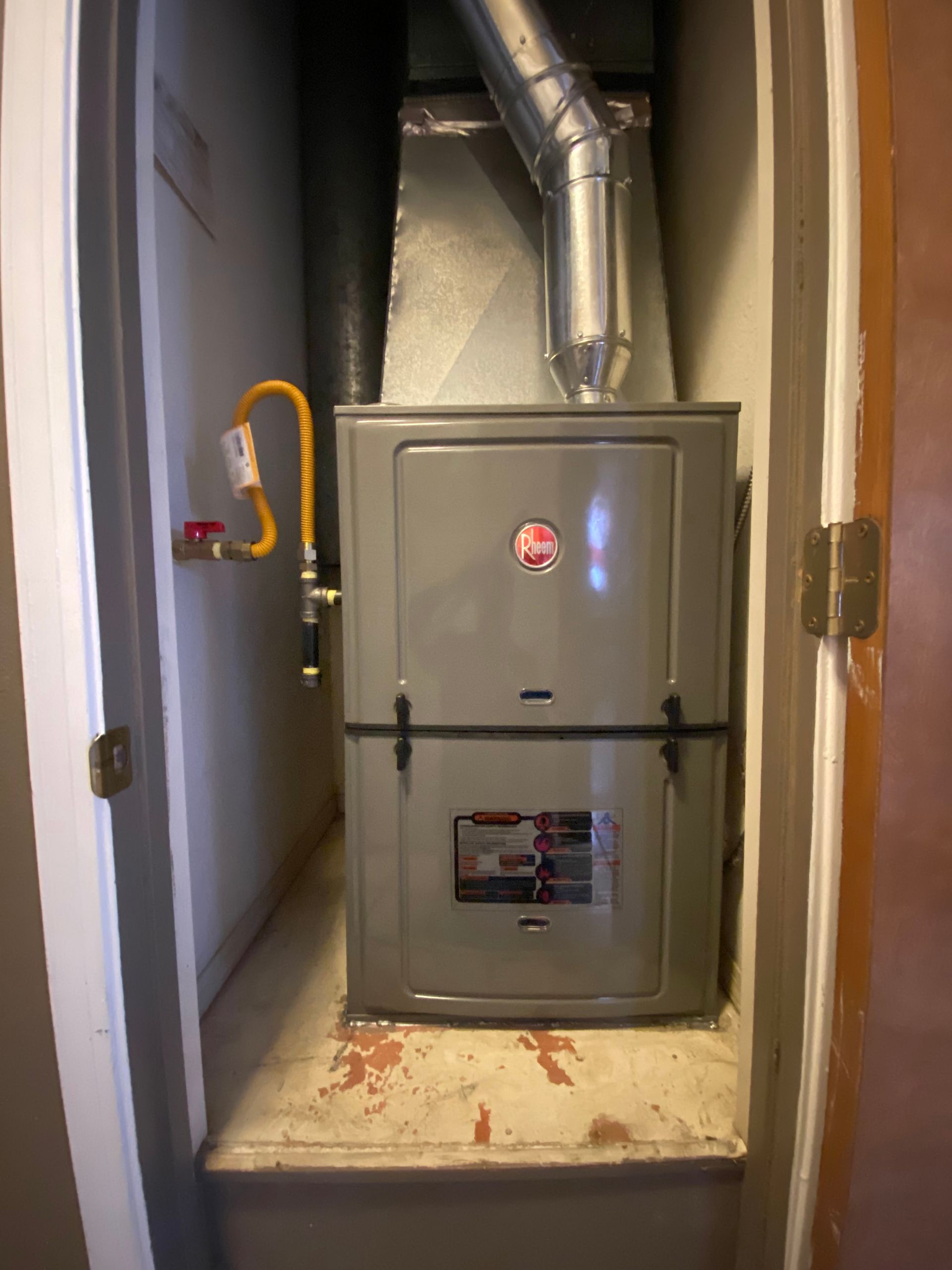 A furnace is sitting in a closet next to a door.