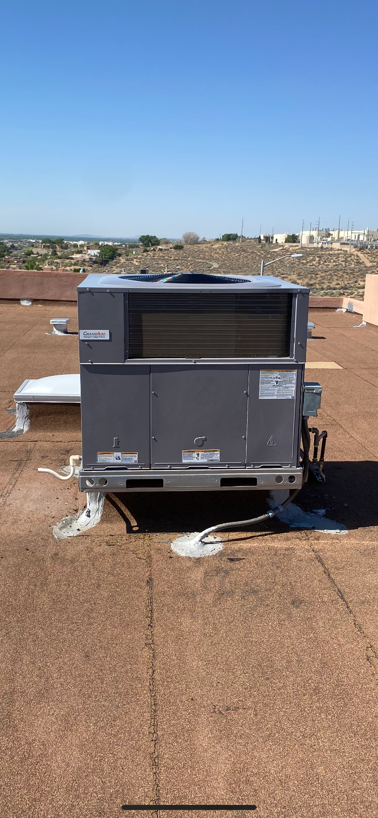 A large air conditioner is sitting on top of a roof.