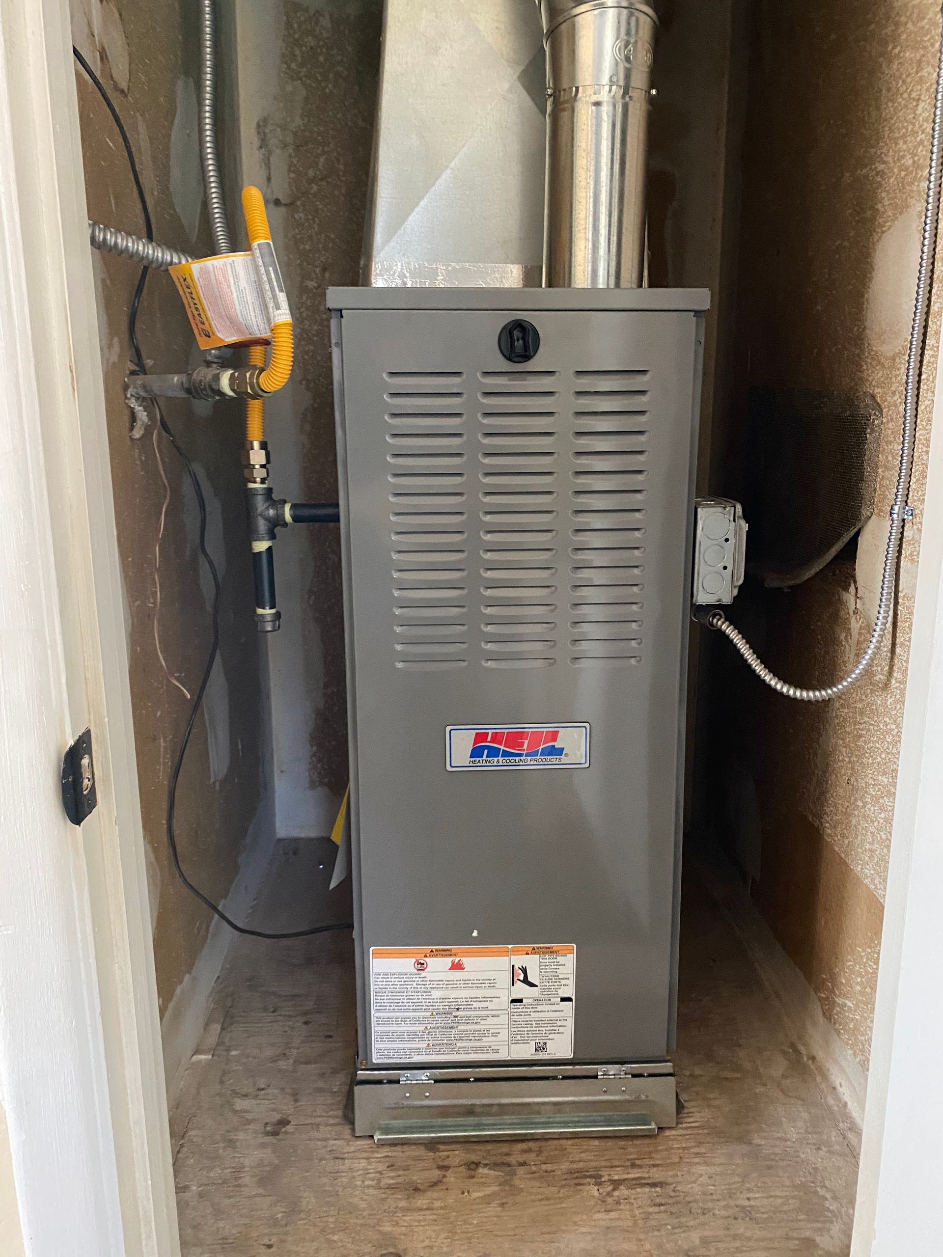 A gas heater is sitting in a corner of a room.
