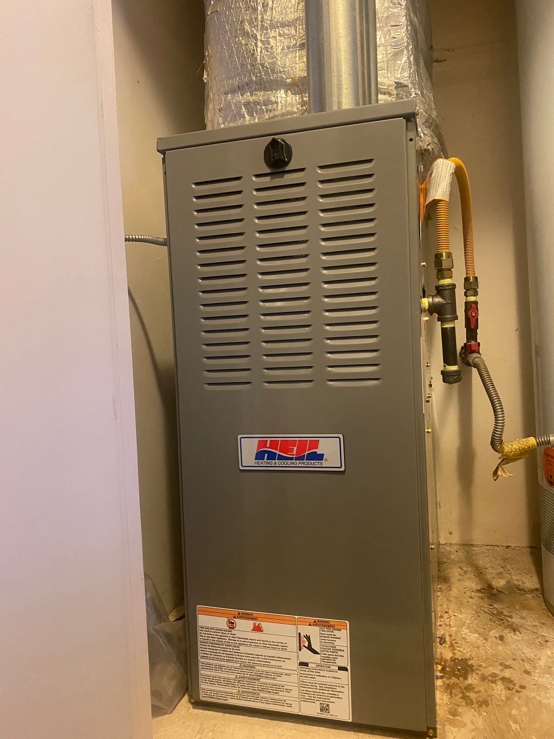 A person is working on an air conditioner with gauges attached to it.
