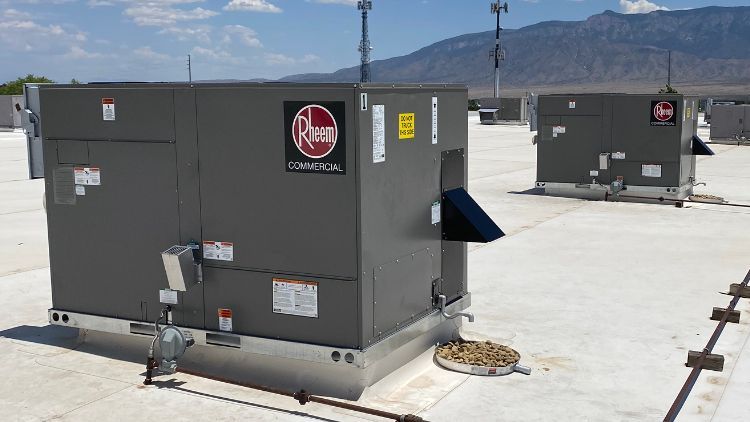 Two rheem air conditioners are sitting on top of a roof.