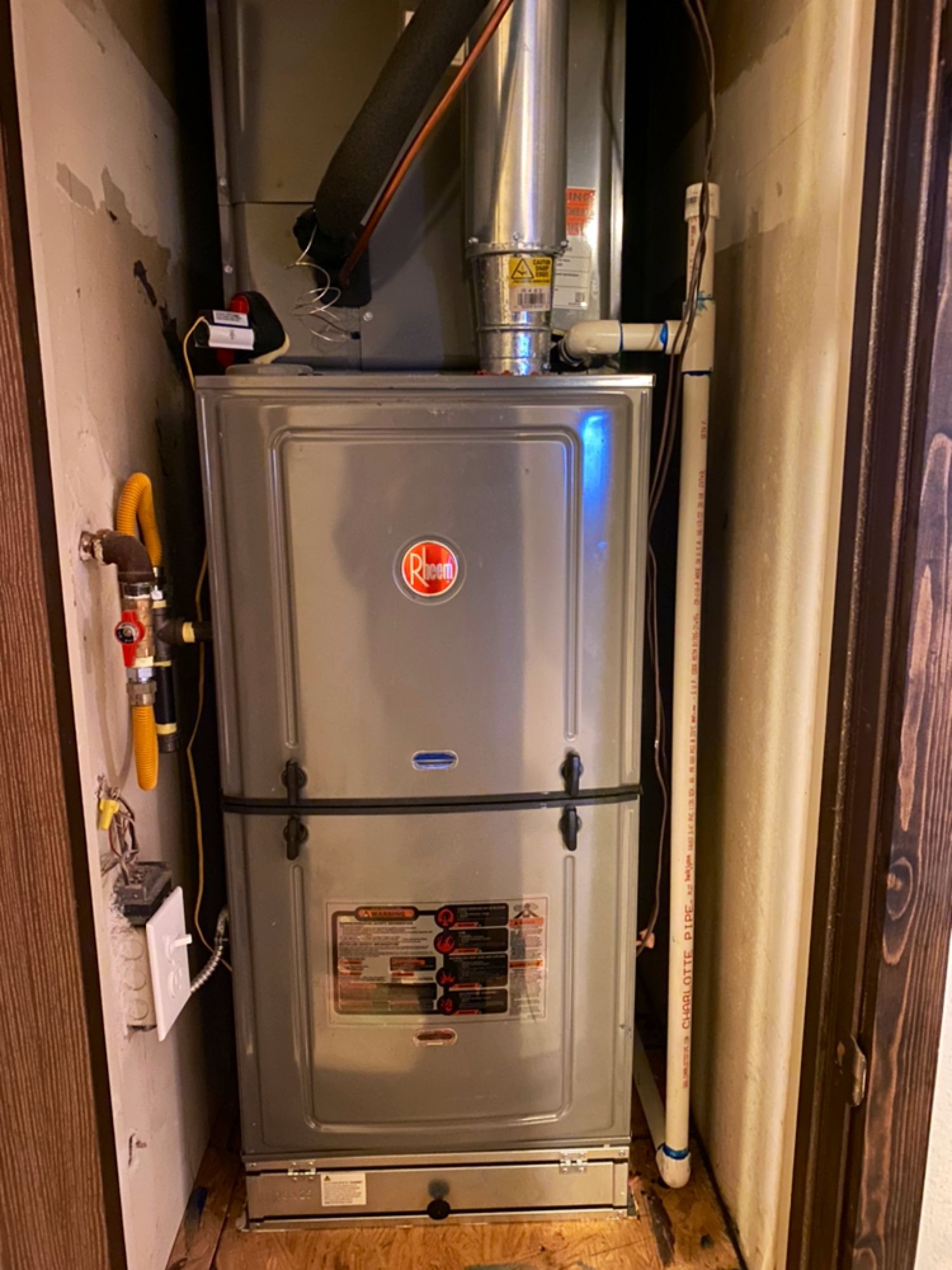 A stainless steel air conditioner is sitting in a closet next to a door.
