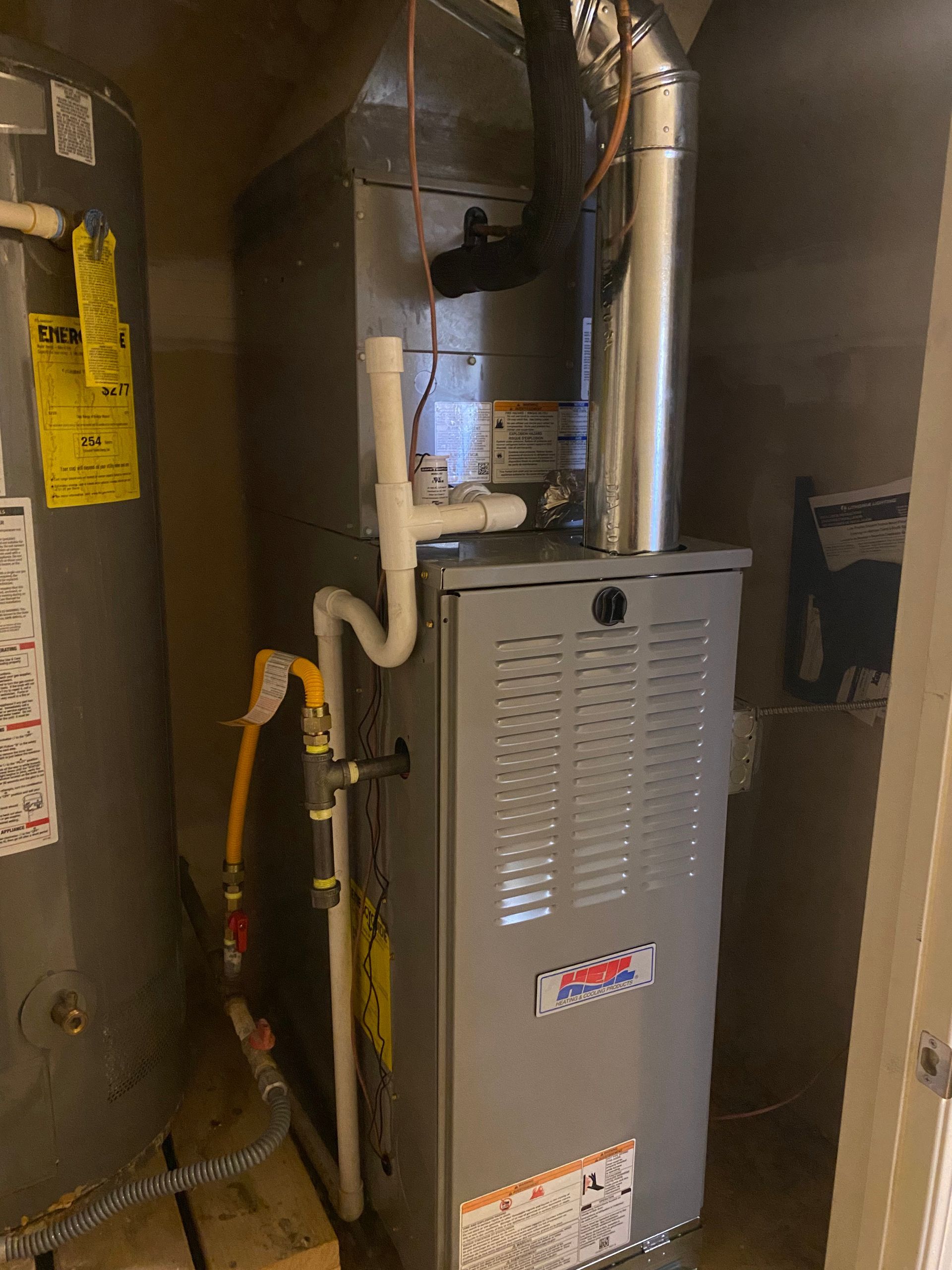 A furnace is sitting in a closet next to a water heater.
