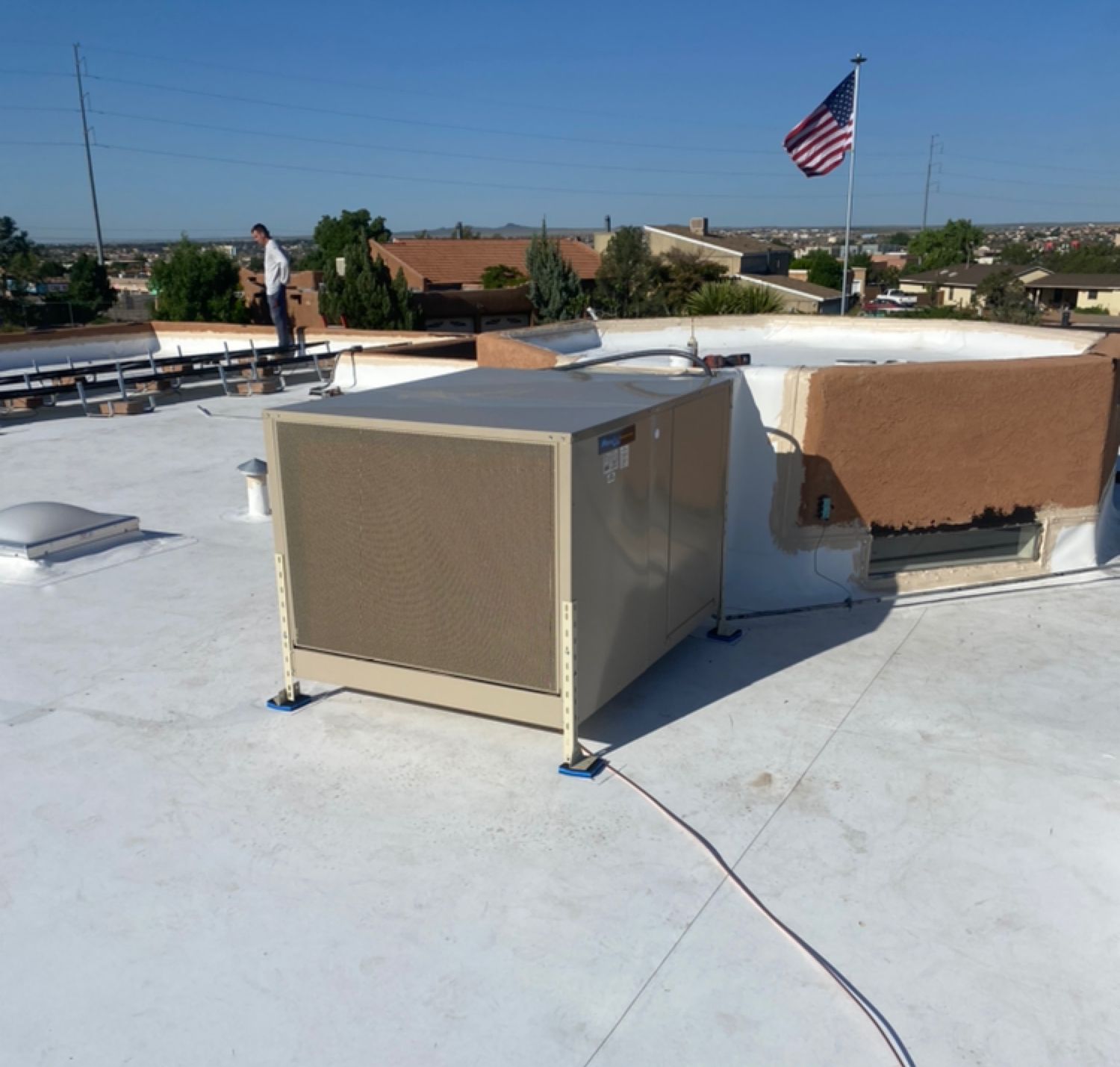 A man stands on a roof with an american flag in the background