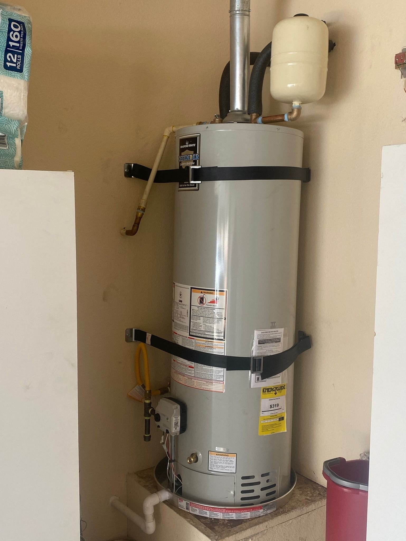 A water heater is sitting on a shelf in a room next to a wall.