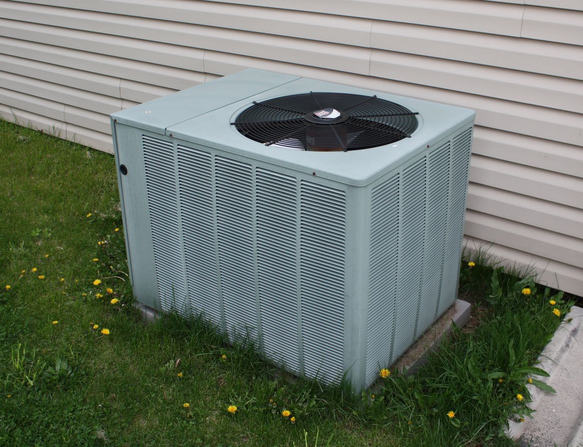 An air conditioner is sitting on the side of a house.