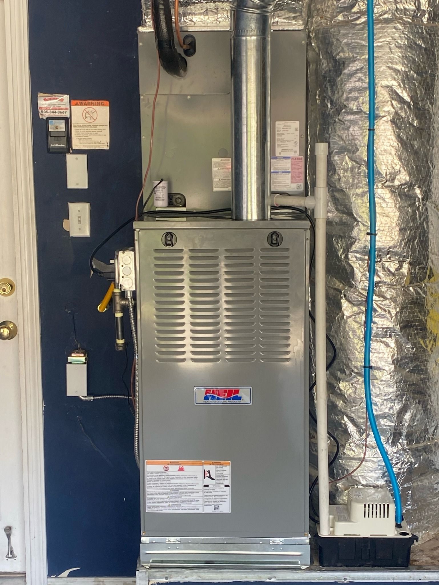 An air conditioner is sitting in a garage next to a door.