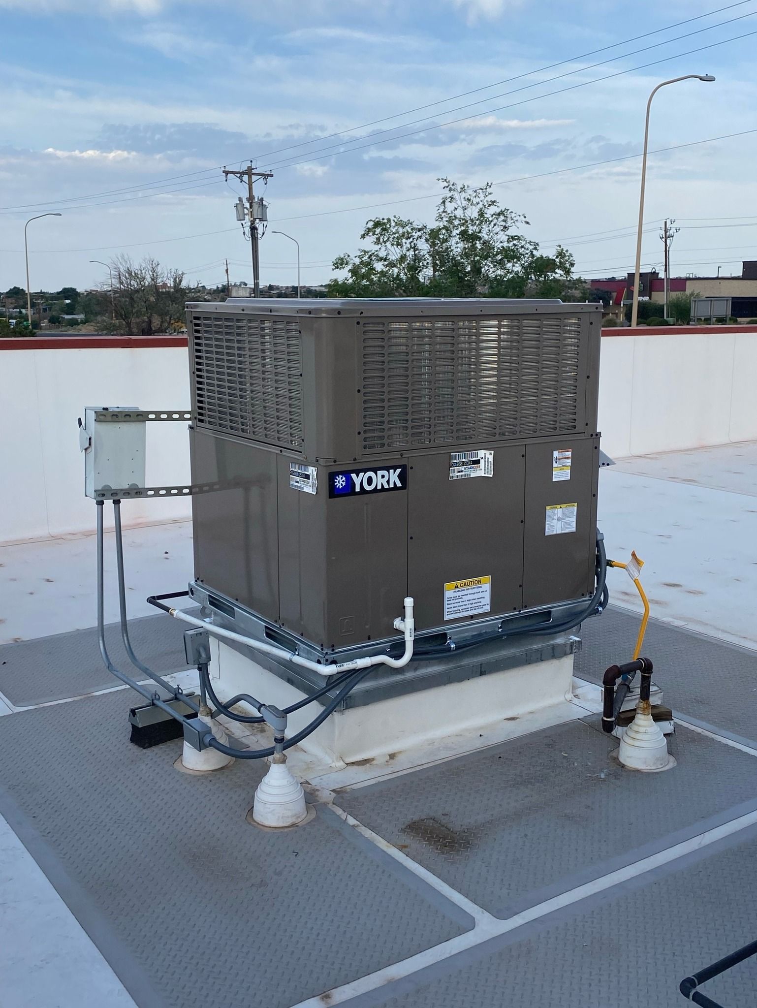 A large air conditioner is sitting on top of a roof in a parking lot.