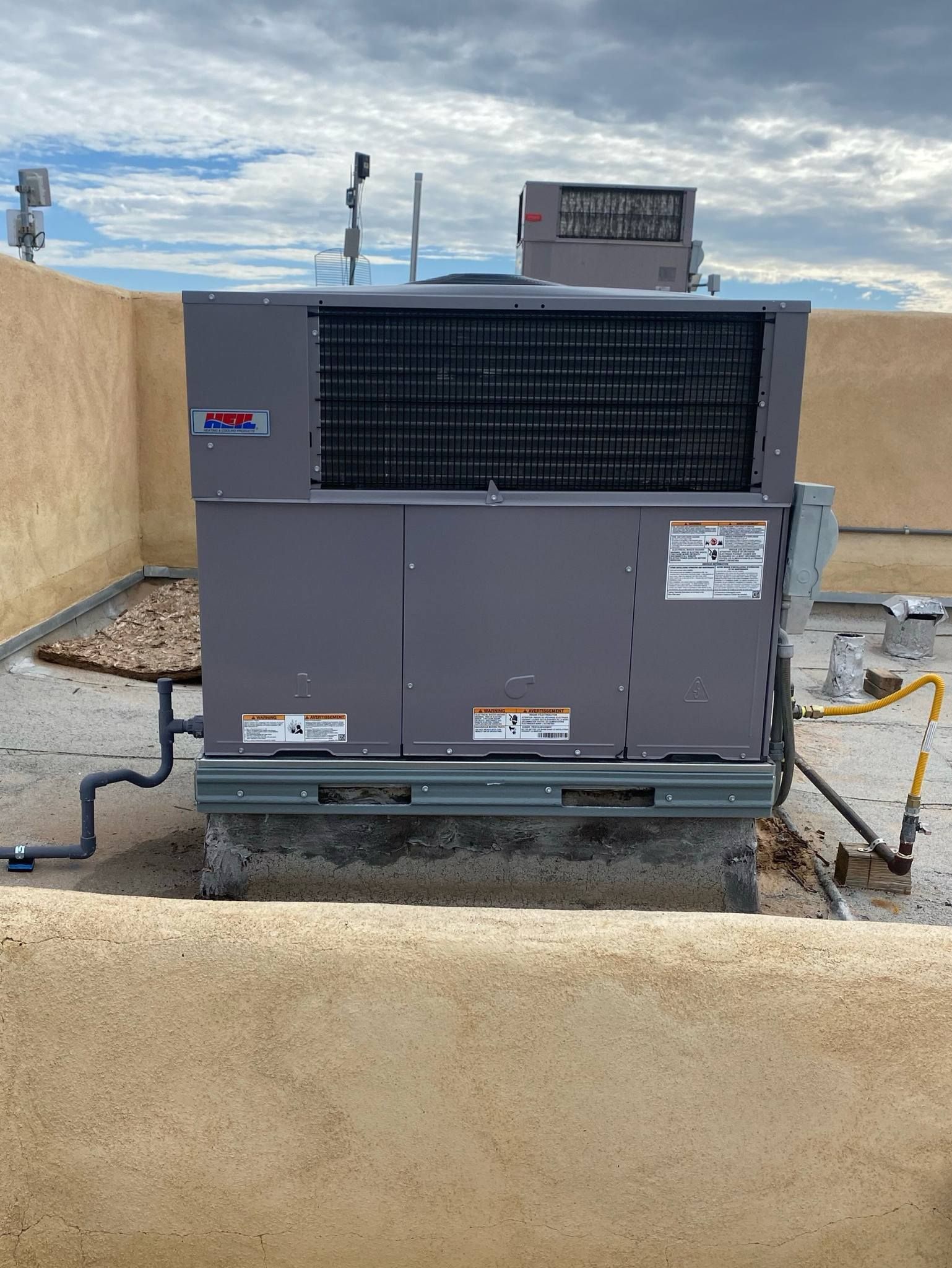 A large air conditioner is sitting on top of a concrete wall.