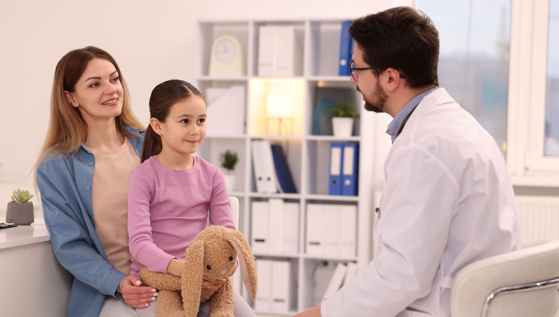 Doctor speaking with a mother and child during a primary care visit.