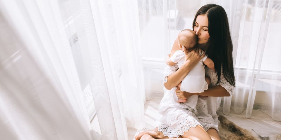 A woman is sitting on the floor holding a baby in her arms.