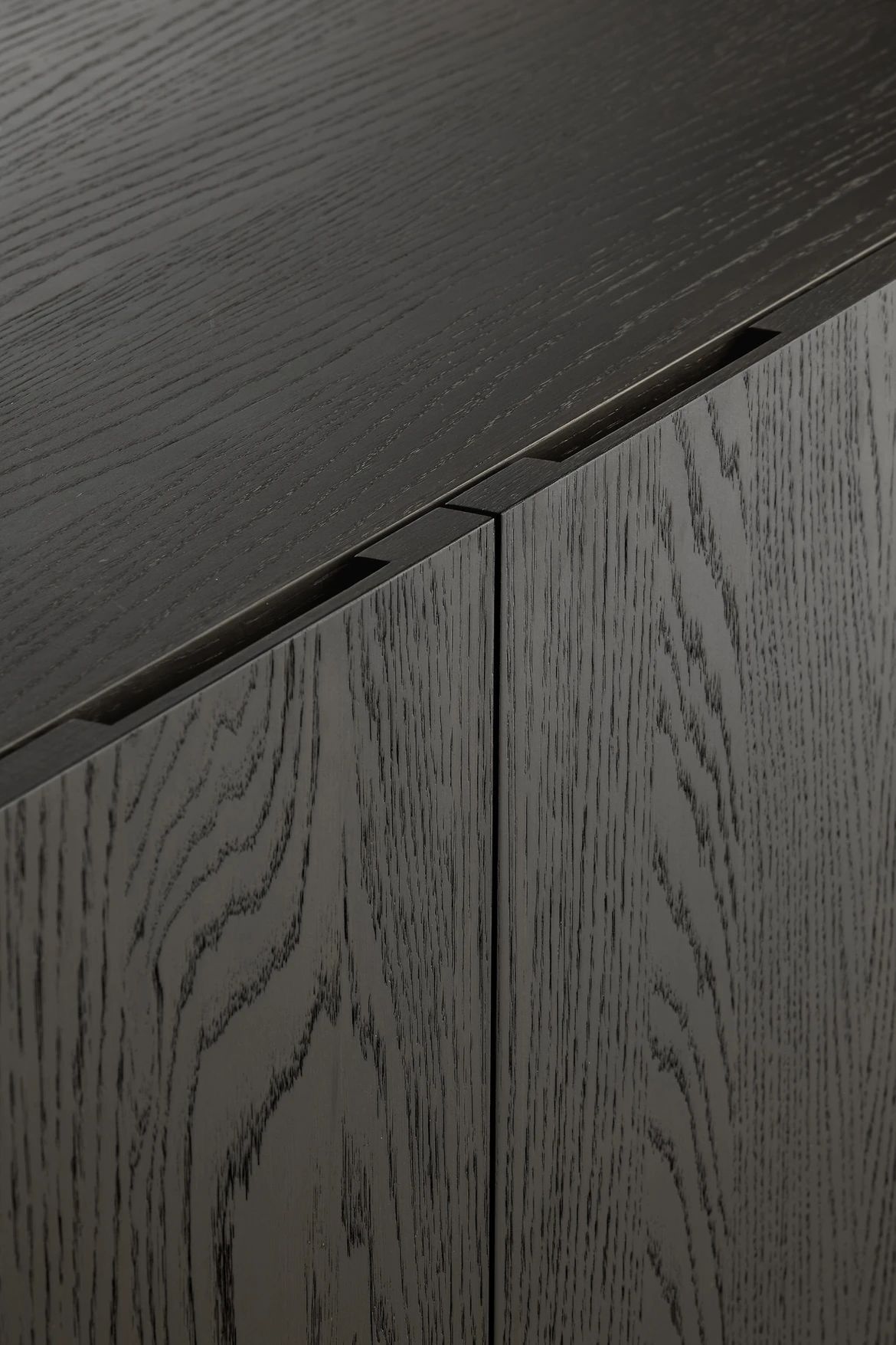 Modern gray and wood-toned kitchen with built-in oven, sink, and counter with flowers.