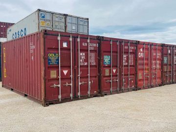 A row of shipping containers are lined up in a parking lot.