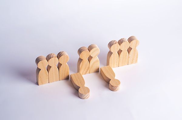 A group of wooden people standing next to each other on a white background.