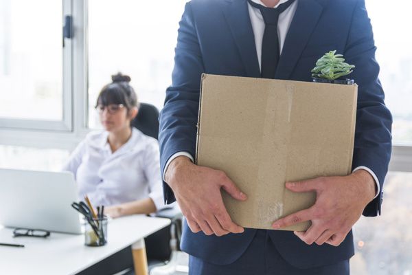 A man in a suit and tie is holding a cardboard box in his hands.