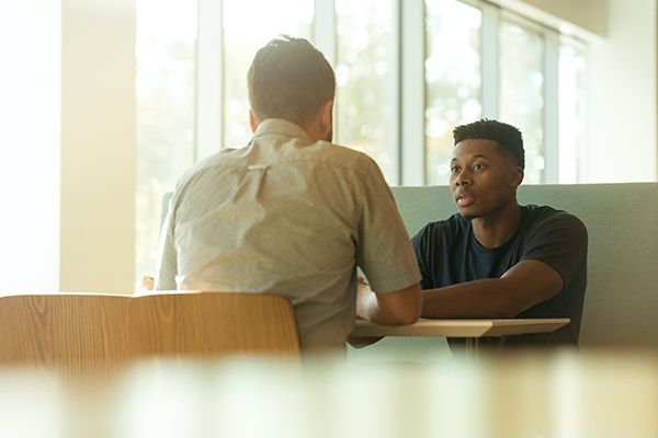 Two men are sitting at a table having a conversation.